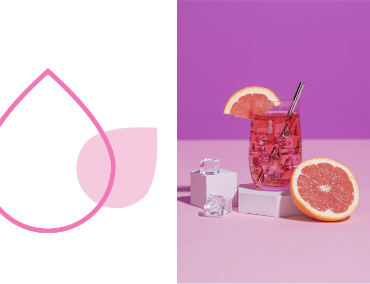 Un cocktail couleur pamplemousse vif avec une moitié de pamplemousse coupée rouge rubis.